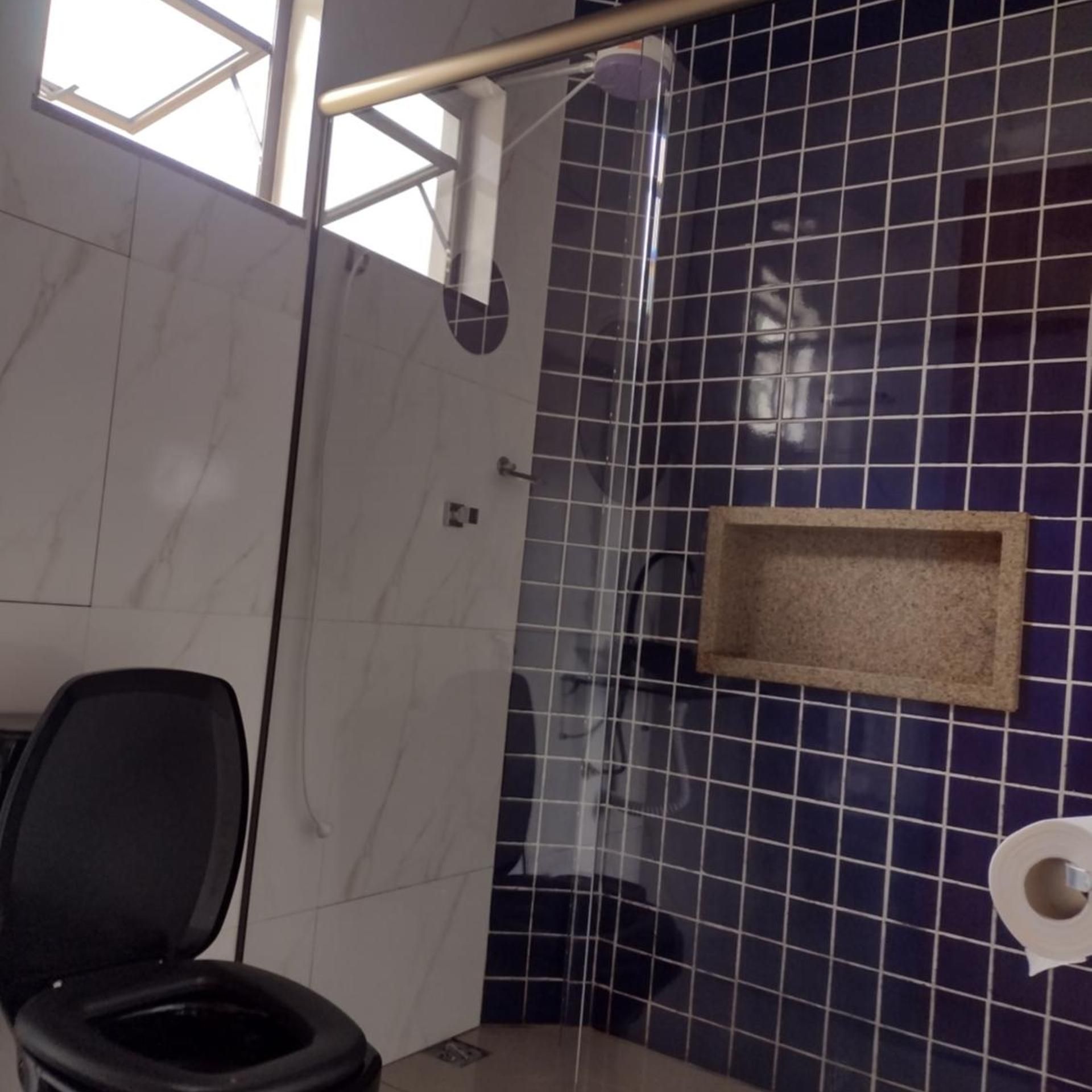Casa de banho com sanita, zona de duche e um porta-toalhas.