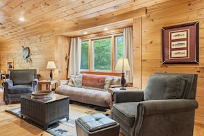 A cozy cabin interior with wooden walls, a sofa, two armchairs, a coffee table, and a fireplace. - Seven Feathers A Modern Barn Retreat/ Pet & Family Friendly (Blue Ridge)