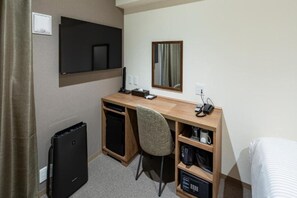 A hotel room with a wooden desk, a chair, a television mounted on the wall, a mirror, a small shelf with a coffee maker, and a bed. - Hotel Reference Tenjin III (Fukuoka)