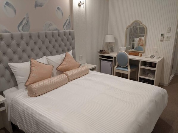 A neatly arranged bedroom with a tufted headboard, a bed with white bedding and decorative pillows, a desk with a chair, and a mirror. - Hotel Reference Tenjin III (Fukuoka)