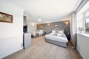 A modern hotel room with a large bed, a smaller bed, a desk, and a television. - The Greyhound Hotel Leigh (Leigh)