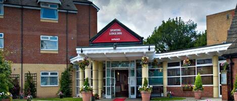 A brick building with a red entrance sign for Sporting Lodge Inns.