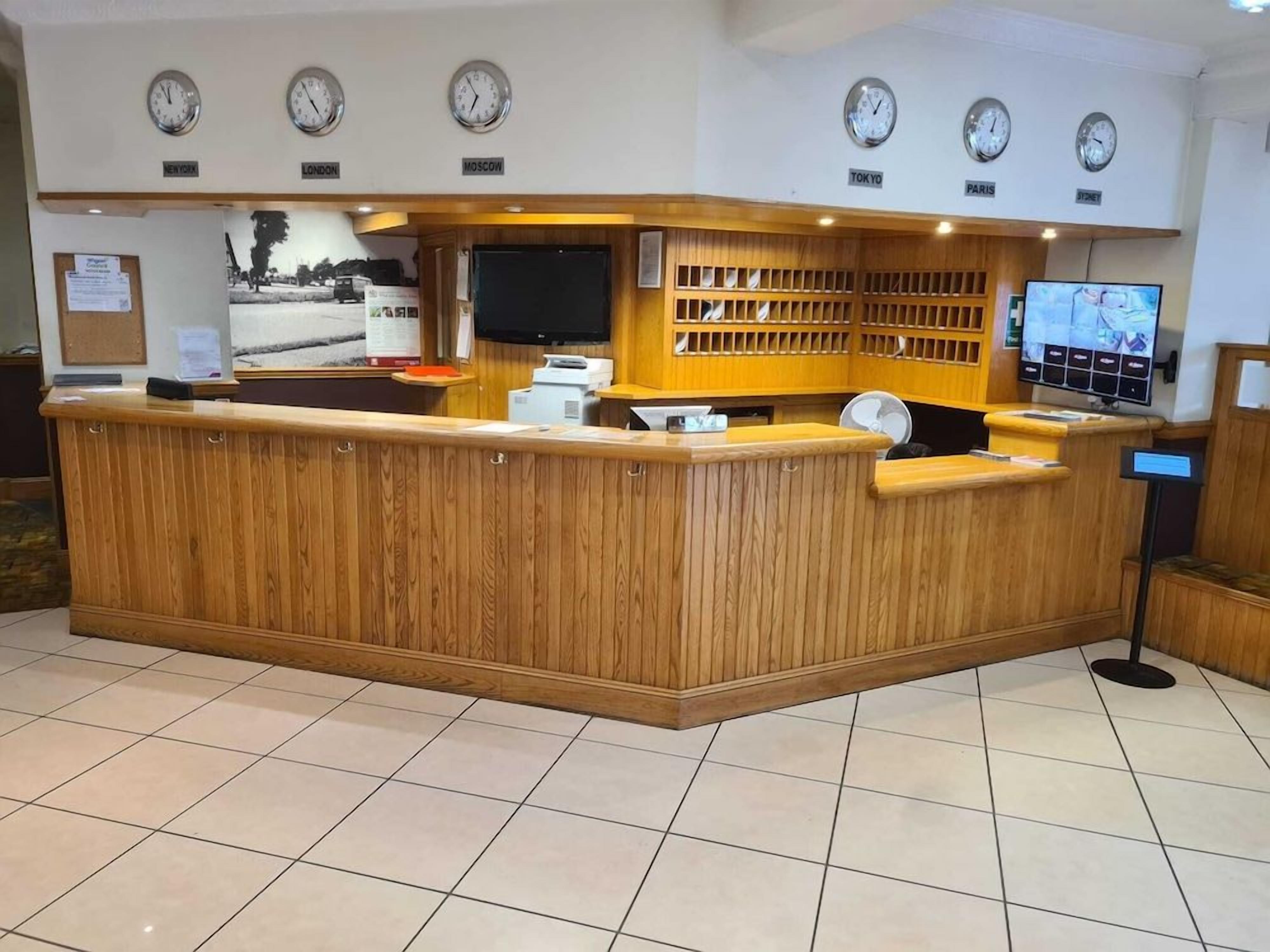 A reception desk with clocks displaying times for New York, London, Moscow, Tokyo, Paris, and Sydney.