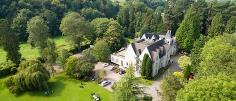 A large estate with multiple buildings, surrounded by lush greenery and a well-maintained lawn.