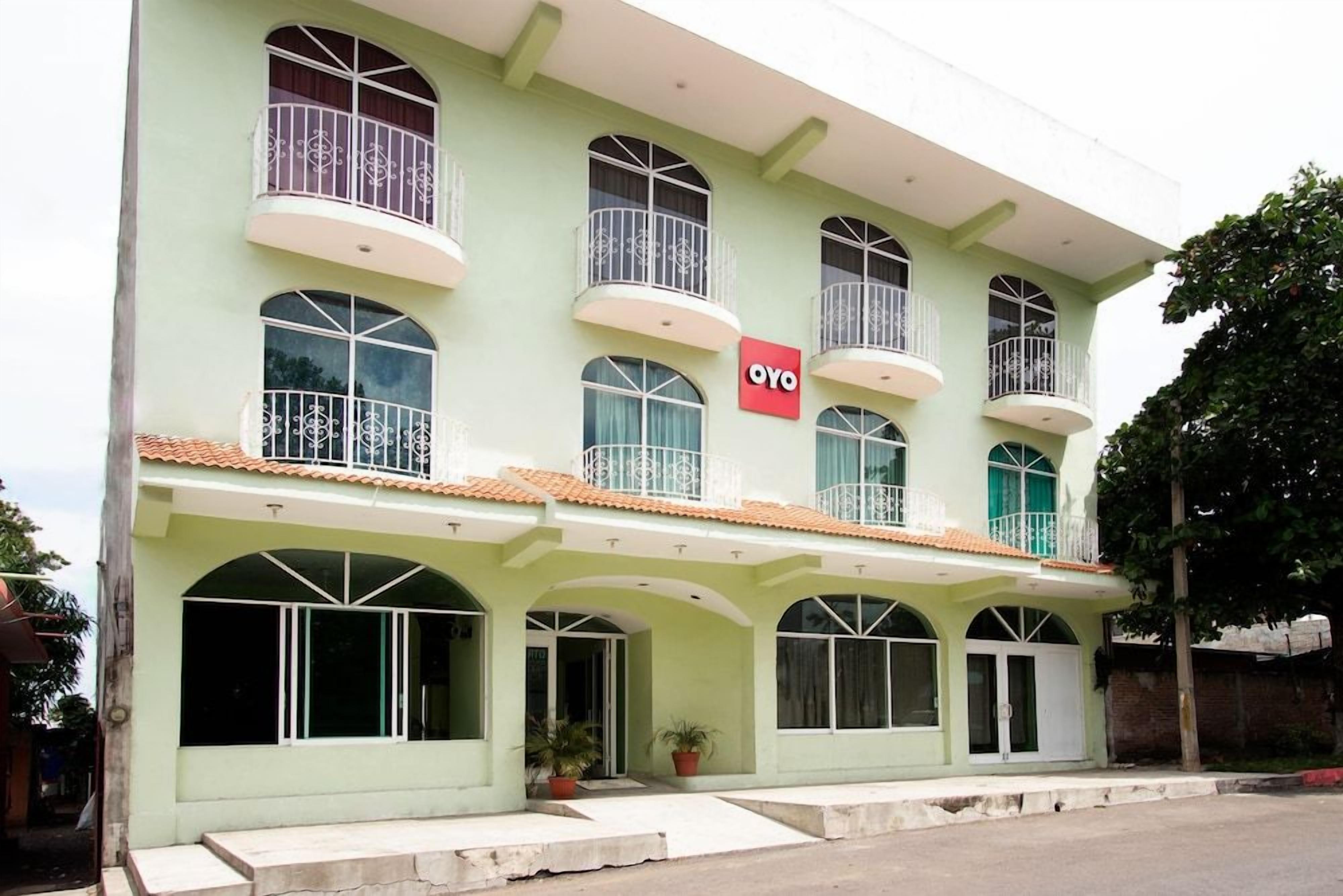 Un edificio de dos pisos con balcones, un letrero que dice 'OYO' y ventanas amplias.