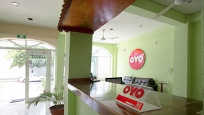 A reception area with a reception desk, a potted plant, a wall-mounted sign, and a seating area with a sofa. - OYO Hotel Estacion (La Antigua)