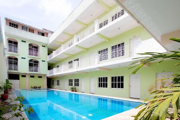 Um edifício com vários andares, piscina, varandas e portas.