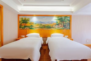 A hotel room with two single beds, a large landscape painting on the wall, and a wooden floor. - Vienna International Hotel Kunming (Kunming)