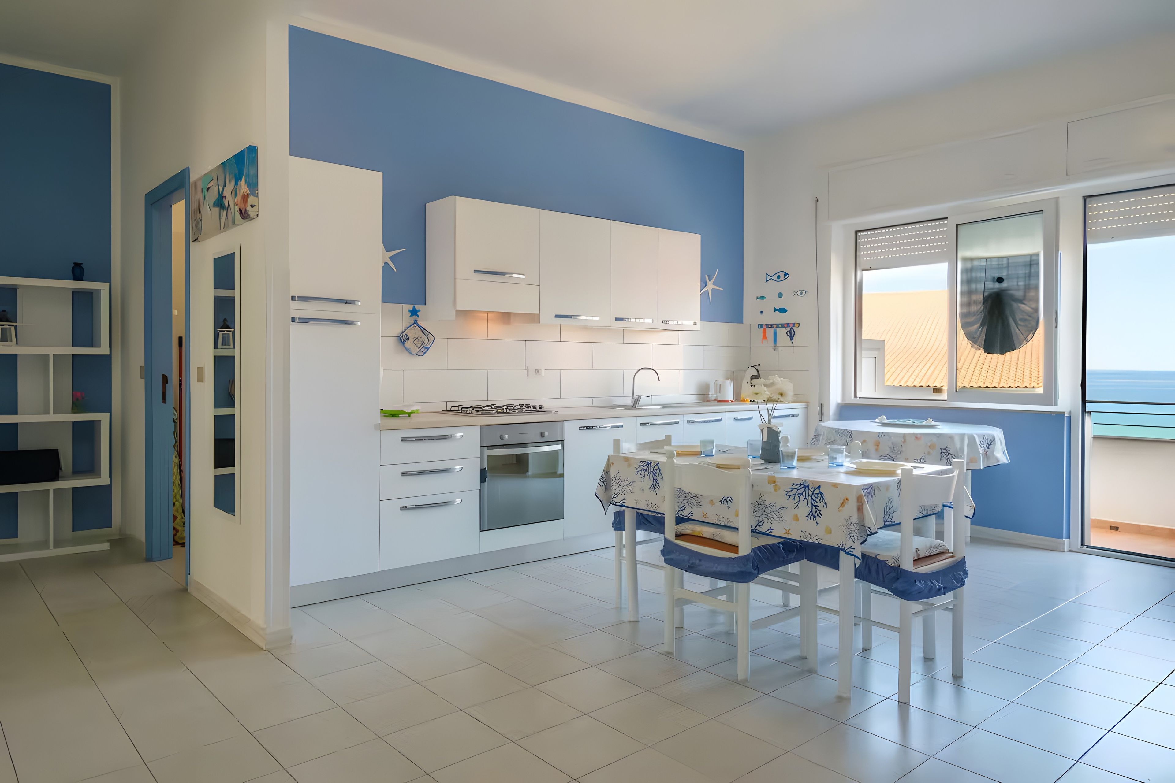 A modern kitchen with white cabinets, a gas stove, and a dining area with a table and chairs.