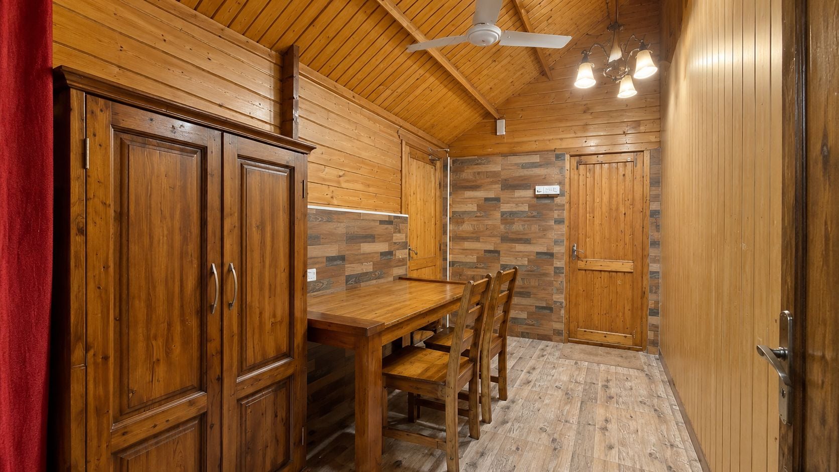 A wooden interior with a dining table, chairs, and cabinets.