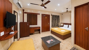 A hotel room with a bed, a desk, a television, and a ceiling fan.