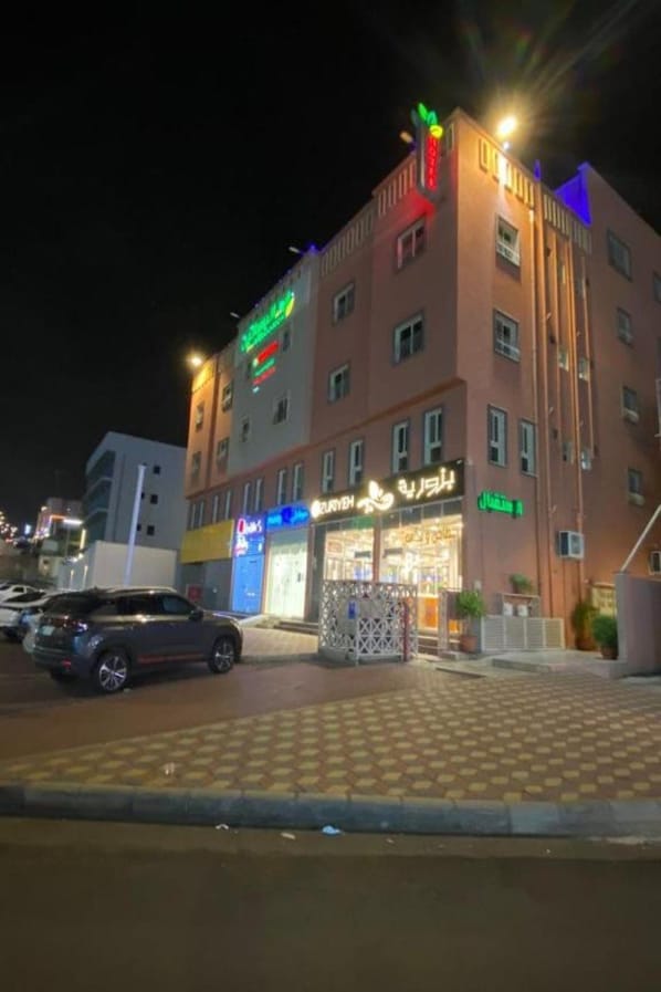 Ein mehrstöckiges Hotel mit auffälliger Beschilderung, einer überdachten Außenbereich und einem Parkplatz.