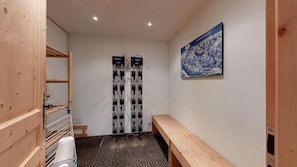 A room with a wooden bench, a ski lift, and a wall-mounted painting.