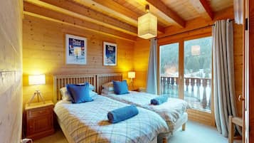 Une chambre dans un chalet en bois, avec deux lits, une fenêtre donnant sur un paysage agréable et un balcon.
