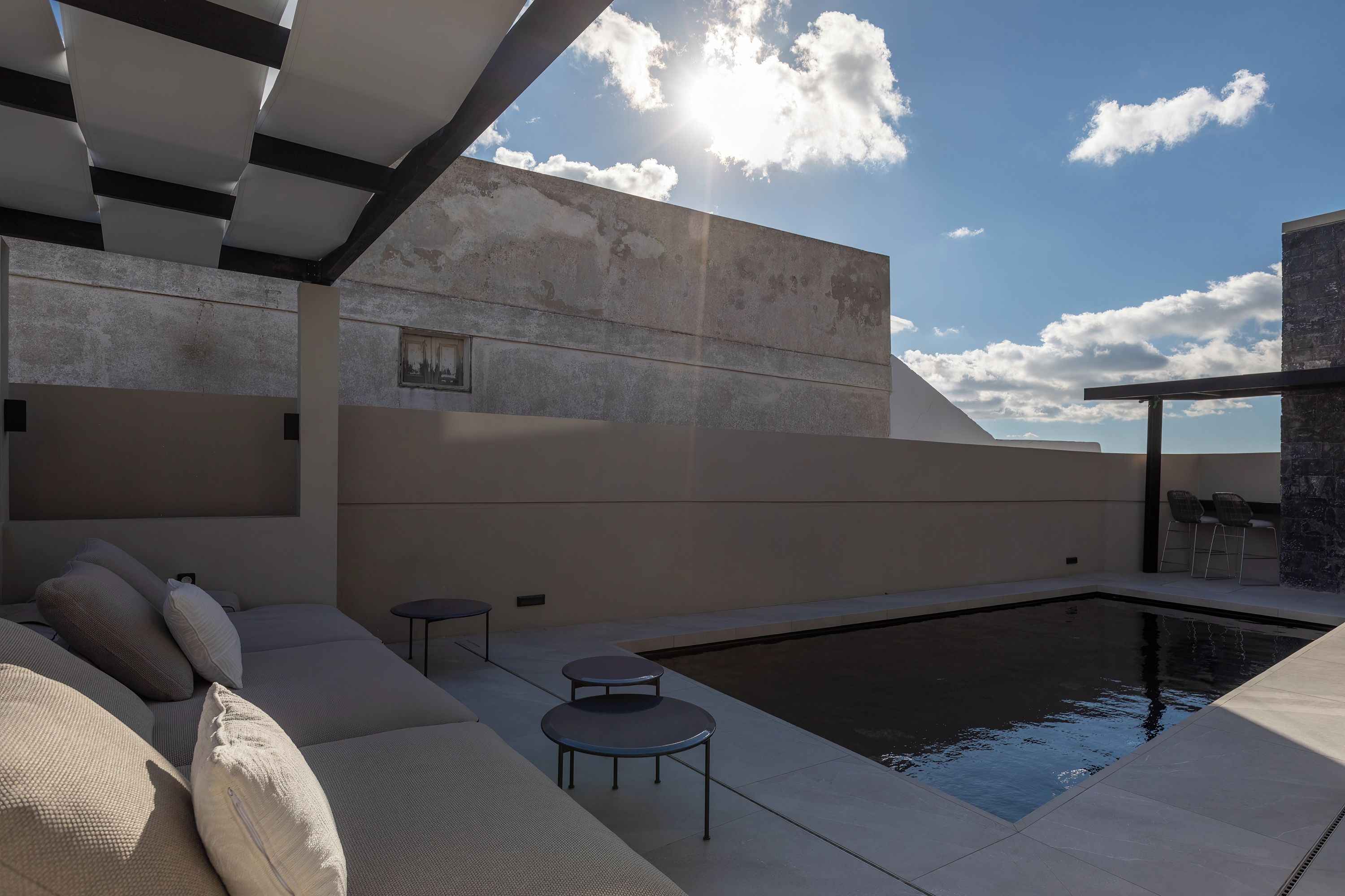 Un'area relax esterna moderna con piscina, un divano e un tavolino.