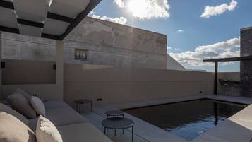 Un'area relax esterna moderna con piscina, un divano e un tavolino.