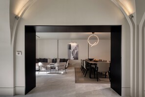 Un intérieur moderne comprenant un coin repas, un ensemble de canapés et une œuvre d’art murale originale.