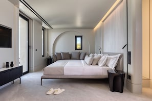 Une chambre moderne avec un grand lit, des tables de chevet, une télévision et une fenêtre.