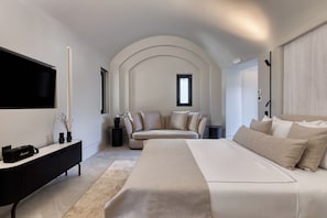 Une chambre moderne comprenant un lit, un téléviseur, une console et un coin salon avec un canapé.