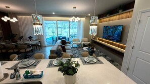A modern dining area with a central island, dining tables, and chairs. - Brand New Modern 5BR With Pool Game Room 16212 (Clermont)