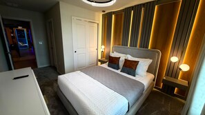 Habitación de hotel con cama, lámparas de noche, una puerta y una pared con listones de madera verticales.
