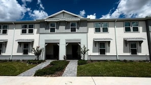 A two-story building with a symmetrical facade, a central entrance with double doors, and a small front garden. - Brand New Modern 5BR With Pool Game Room 16212 (Clermont)