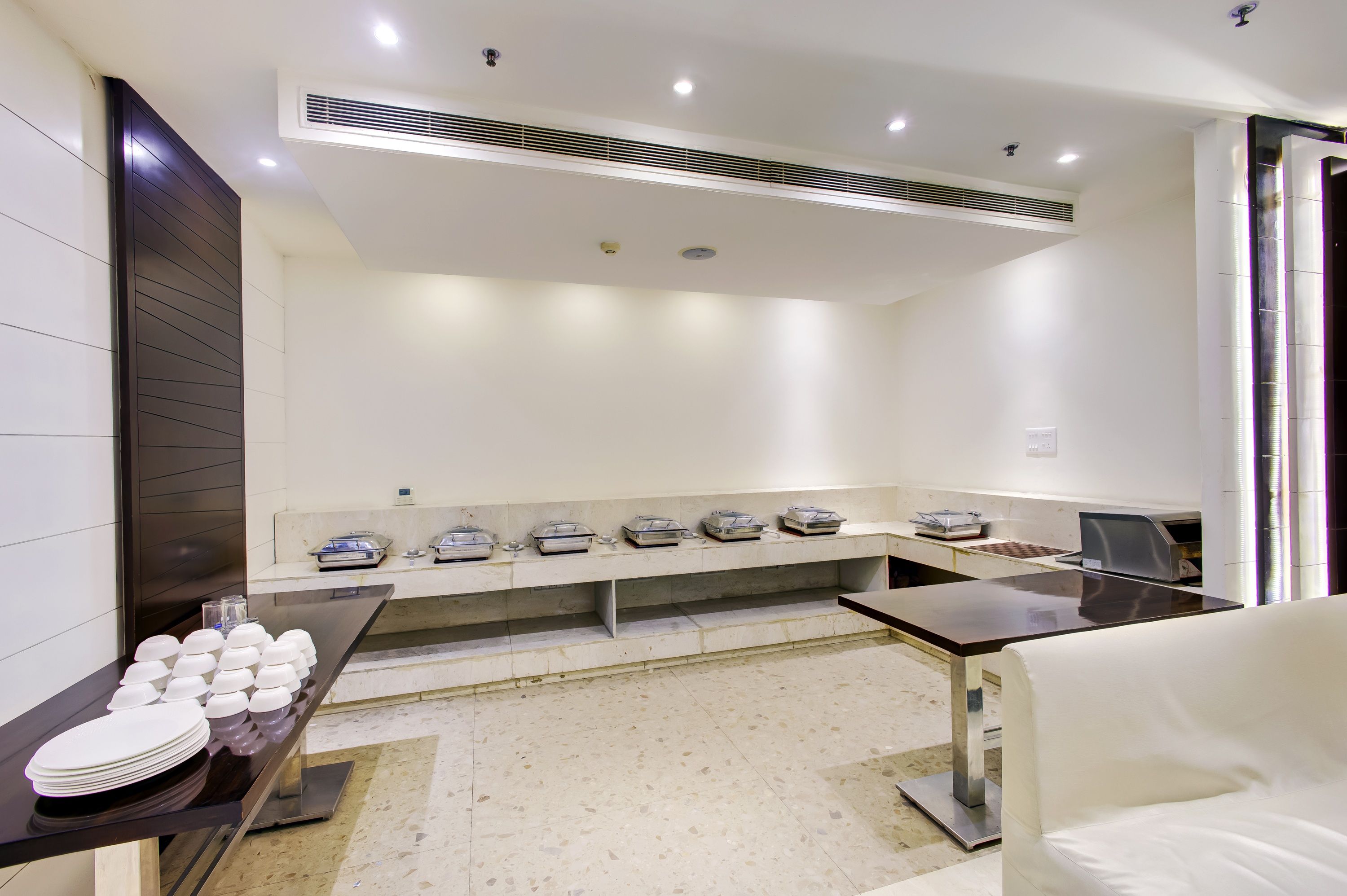 A clean, modern kitchen with a marble countertop, a sink, and a dining area with a white chair.