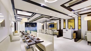 Interior de restaurant modern amb mobiliari blanc, il·luminació penjant i vista cap a l'exterior.
