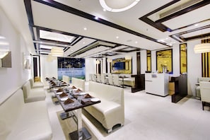 Een modern restaurantinterieur met witte meubels, hanglampen en uitzicht op het exterieur.