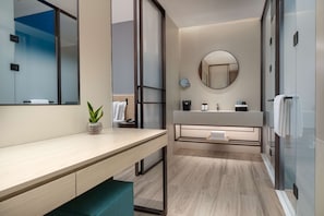 Une salle de bain moderne avec un meuble-lavabo en bois, un miroir rond et une cabine de douche en verre.
