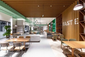 Un intérieur moderne avec un espace salon central, des éléments décoratifs en bois et un mur d’accent vert sur lequel est inscrit le mot « GOÛT ».