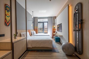 Une chambre d’hôtel moderne équipée d’un grand lit, d’un ballon de gymnastique et d’un appareil d’exercice fixé au mur.