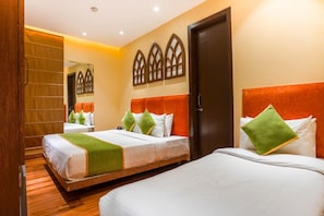 Habitación de hotel con dos camas, piso de madera, un espejo grande y una puerta.