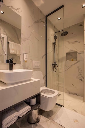 Een moderne badkamer met een wit wastafel, toilet en douchecabine met glazen wanden.