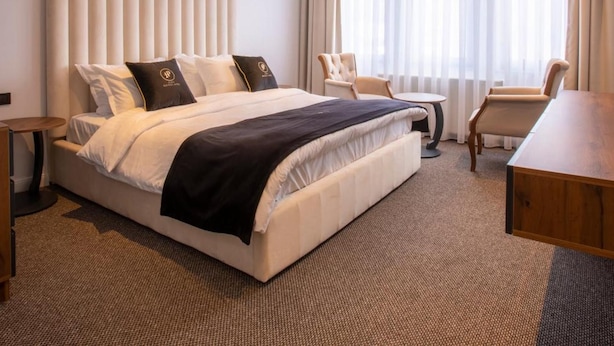 A modern hotel room with a large bed, a desk, and a chair. - Plaza Boutique Hotel Prishtina (Pristina)