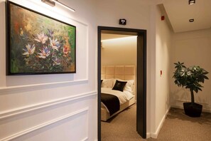 Ett hotellrum med en säng, en krukväxt och en tavla på väggen.