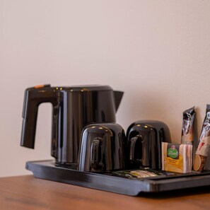 En kaffebryggare med ett fat, en påse te och en påse bröd står på ett bord.