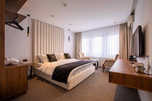 Een hotelkamer met een bed, een bureau, een stoel, een televisie en een minibars.