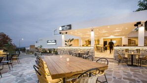 An outdoor dining area with stone flooring and wicker chairs, a bar with a stone wall backdrop, and a sign for 'Sala Pietra Restaurant Bar'. - Ladiko Suites (Rhodes)