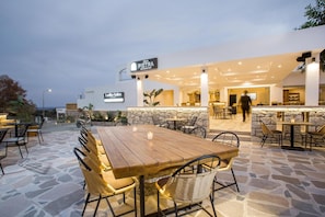 An outdoor dining area with stone flooring and wicker chairs, a bar with a stone wall backdrop, and a sign for 'Sala Pietra Restaurant Bar'. - Ladiko Suites (Rhodes)