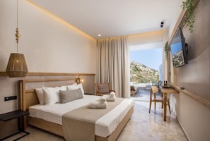A hotel room with a bed, a desk, a chair, a television, and a view of the outdoors. - Ladiko Suites (Rhodes)