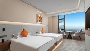 A hotel room with two beds, a small table, and a view of the city. - Hawthorn by Wyndham Honghe Mile Hot Spring (Honghe)