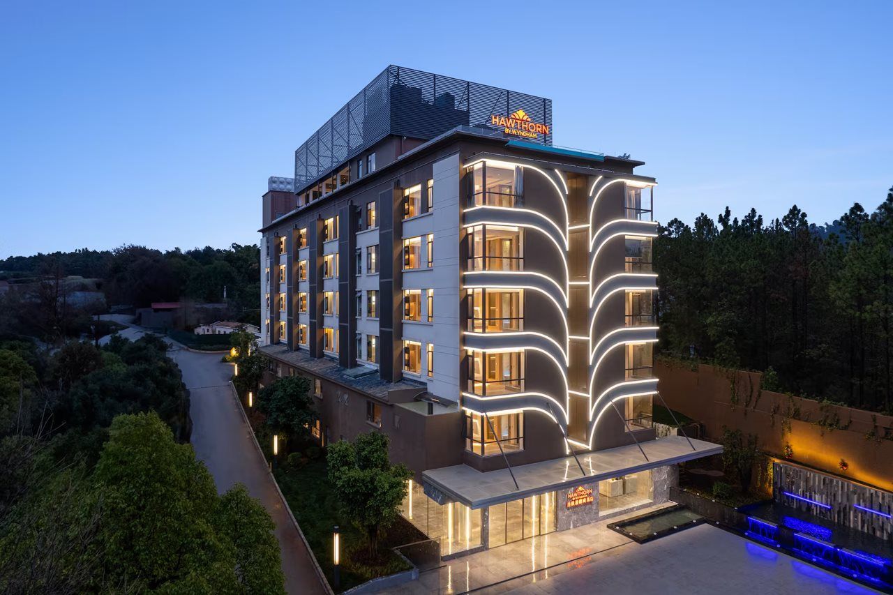 A multi-story hotel with a modern design, featuring a prominent sign on the roof and a well-lit facade.