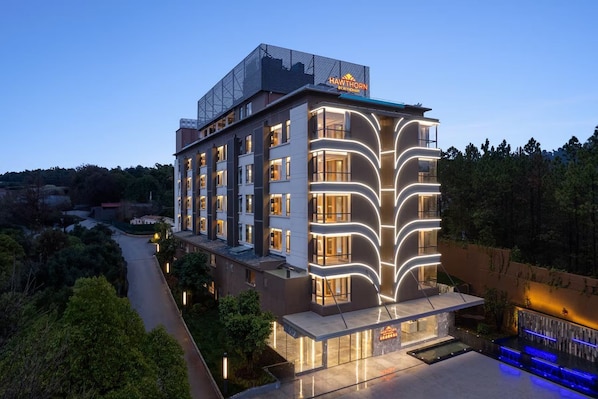A multi-story hotel with a modern design, featuring a prominent sign on the roof and a well-lit facade.