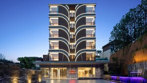 A modern hotel with a symmetrical facade, multiple balconies, and a well-lit entrance. - Hawthorn by Wyndham Honghe Mile Hot Spring (Honghe)