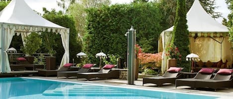 A pool area with lounge chairs and white canopies.