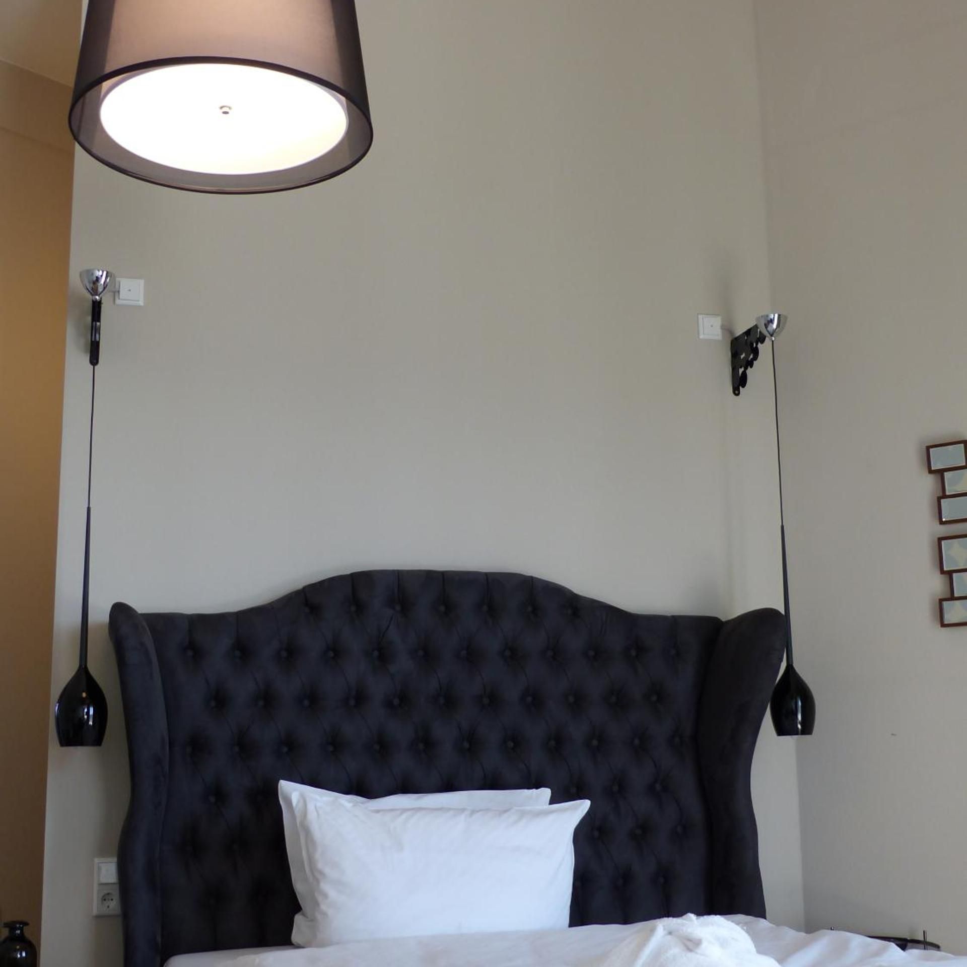 Ein Hotelzimmer mit einem geblümten Kopfteil, einem weißen Kissen und zwei Pendelleuchten.