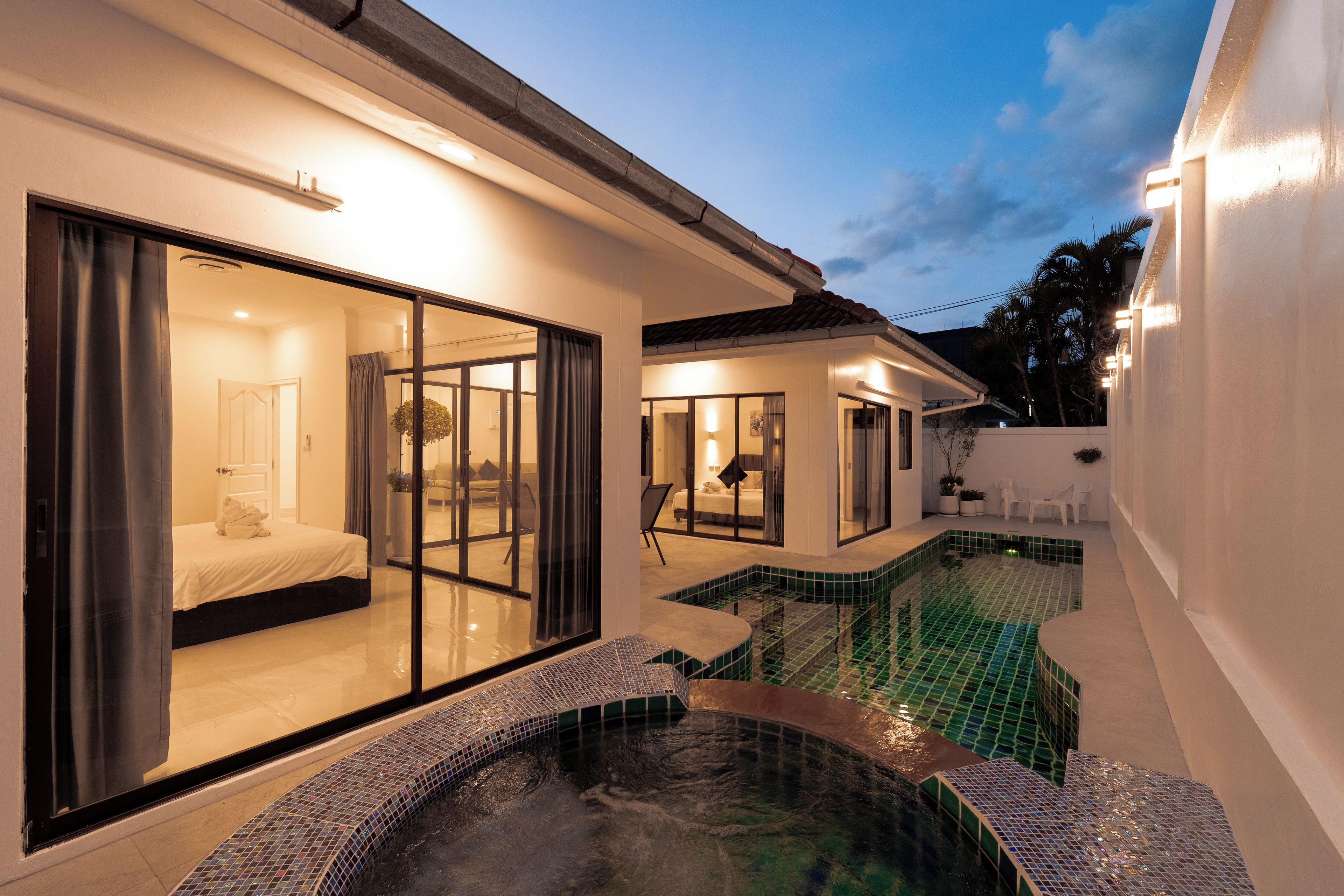 A modern house with a swimming pool, large glass doors, and a well-lit interior.
