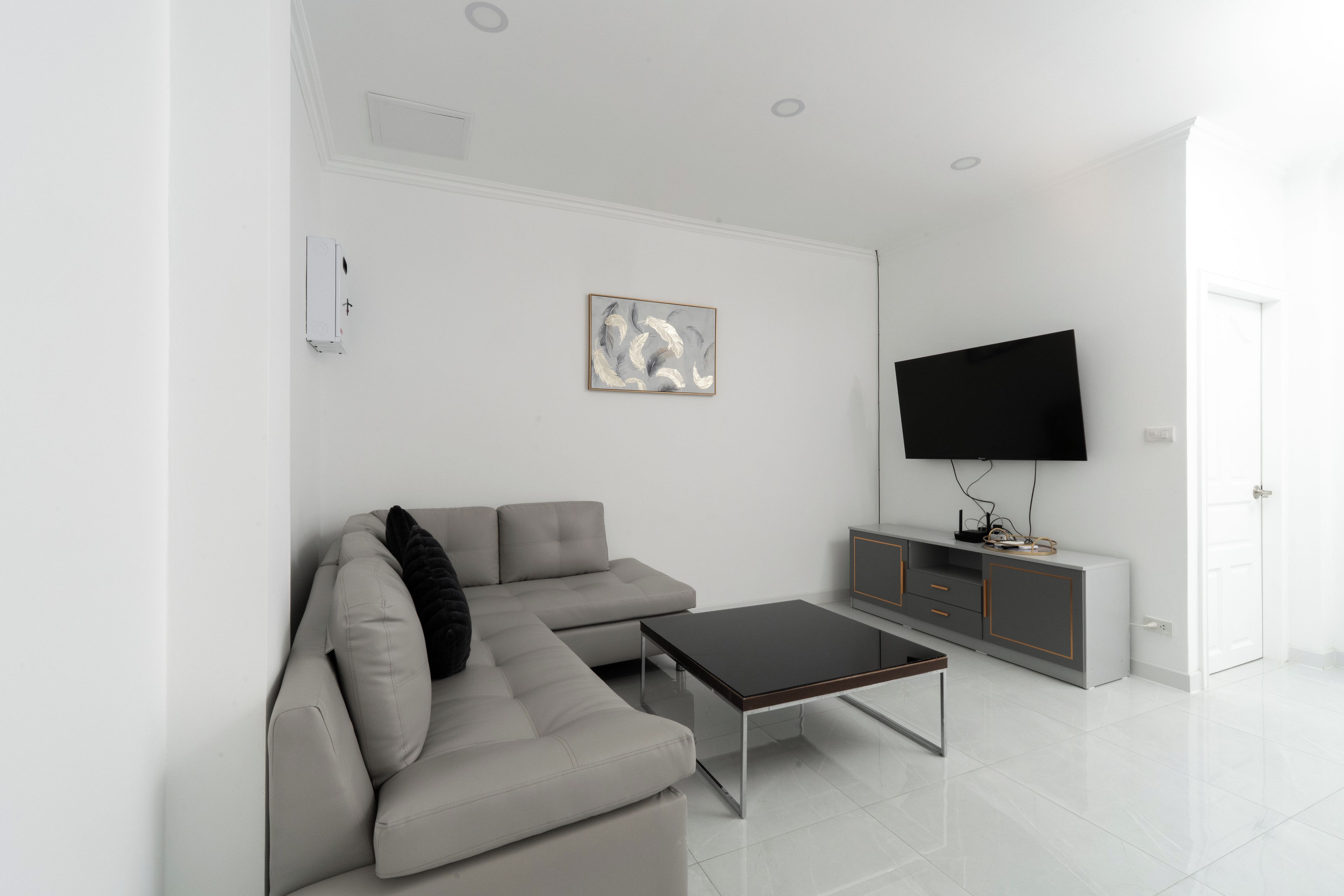 En moderne stue med en modulsofa, et sofabord, et fladskærms-tv og et minimalistisk skab.