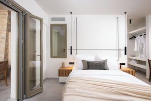 Un dormitorio moderno con una cama grande, una puerta corrediza de vidrio, un armario empotrado y una zona de estar con una silla.